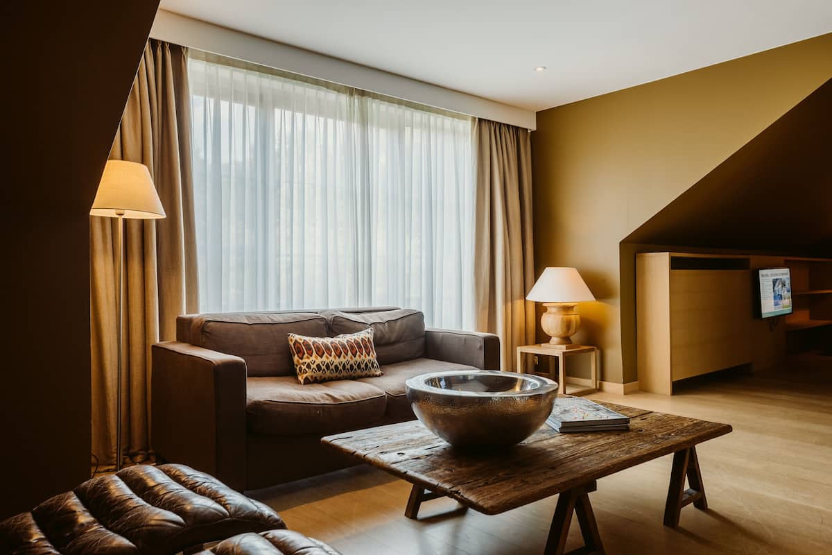 A modern living room with a sofa, a coffee table with a bowl, and a lamp.