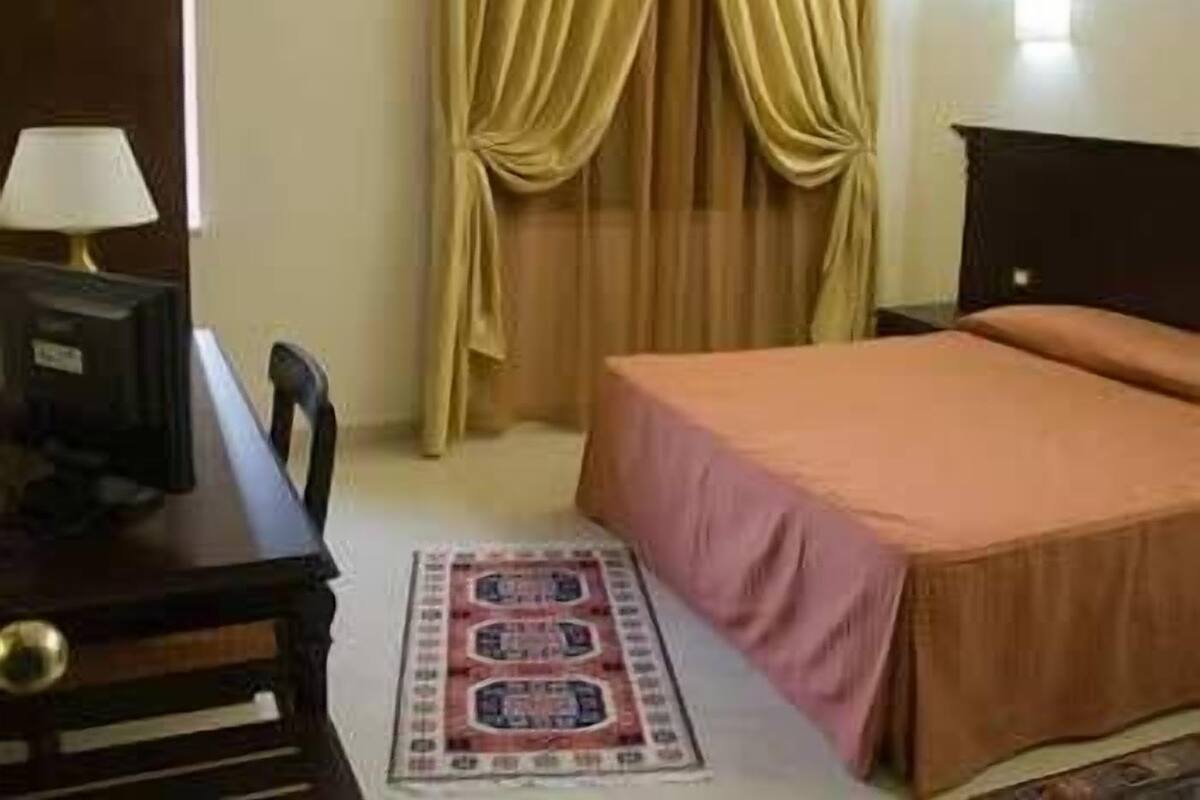 Une chambre d’hôtel avec un lit, un bureau, une lampe et des rideaux.