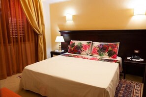 A hotel room with a bed, a nightstand, a lamp, and a wall-mounted light fixture. - Sammartano Hotel (Marsala)
