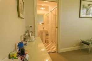 Un baño de hotel con cabina de ducha de vidrio, un lavabo y tocador con espejo.