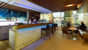 Zona de bar con barra, taburetes y una sala de estar con mesas y sillas.