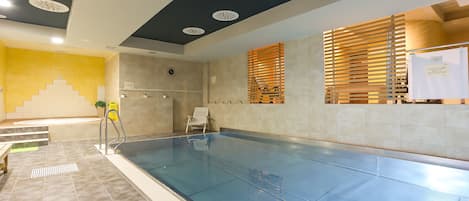 A swimming pool with a tiled floor, a chair, and a wooden slatted window.
