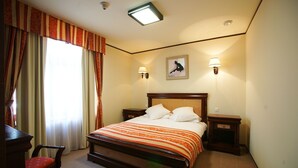 A hotel room with a large bed, two bedside tables, a chair, a painting on the wall, and a window with curtains. - Levoslav House Villa (Sibiu)