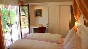 A bedroom with two beds, a desk, and a door leading to a balcony. - Schwarzwaldhotel & Restaurant Stollen (Gutach im Breisgau)