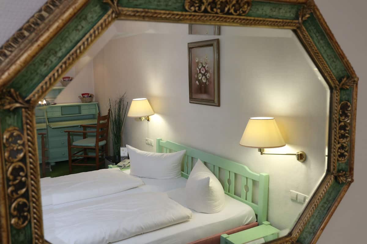 A bedroom with a bed, two bedside lamps, a dresser, and a framed mirror.
