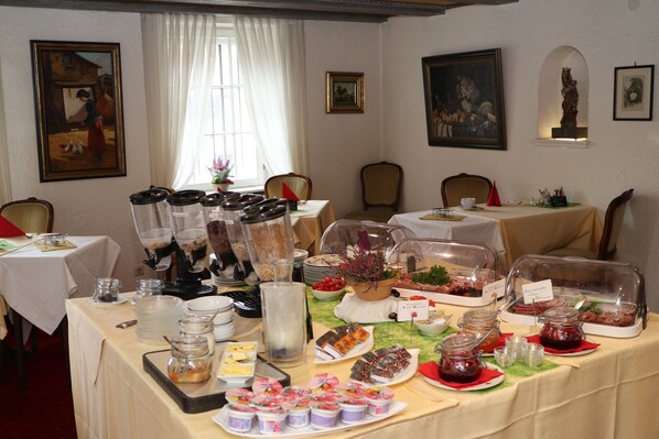 A dining area with tables set for breakfast, featuring various food items and beverages.