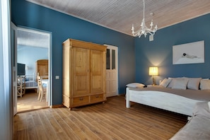 A bedroom with a large wooden wardrobe, a bed, and a chandelier.