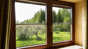 A window with a view of a garden, a bench, and trees. - Karlamuiza Country Hotel (Cesis Municipality)