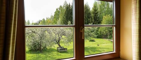 A window with a view of a garden, a bench, and trees.
