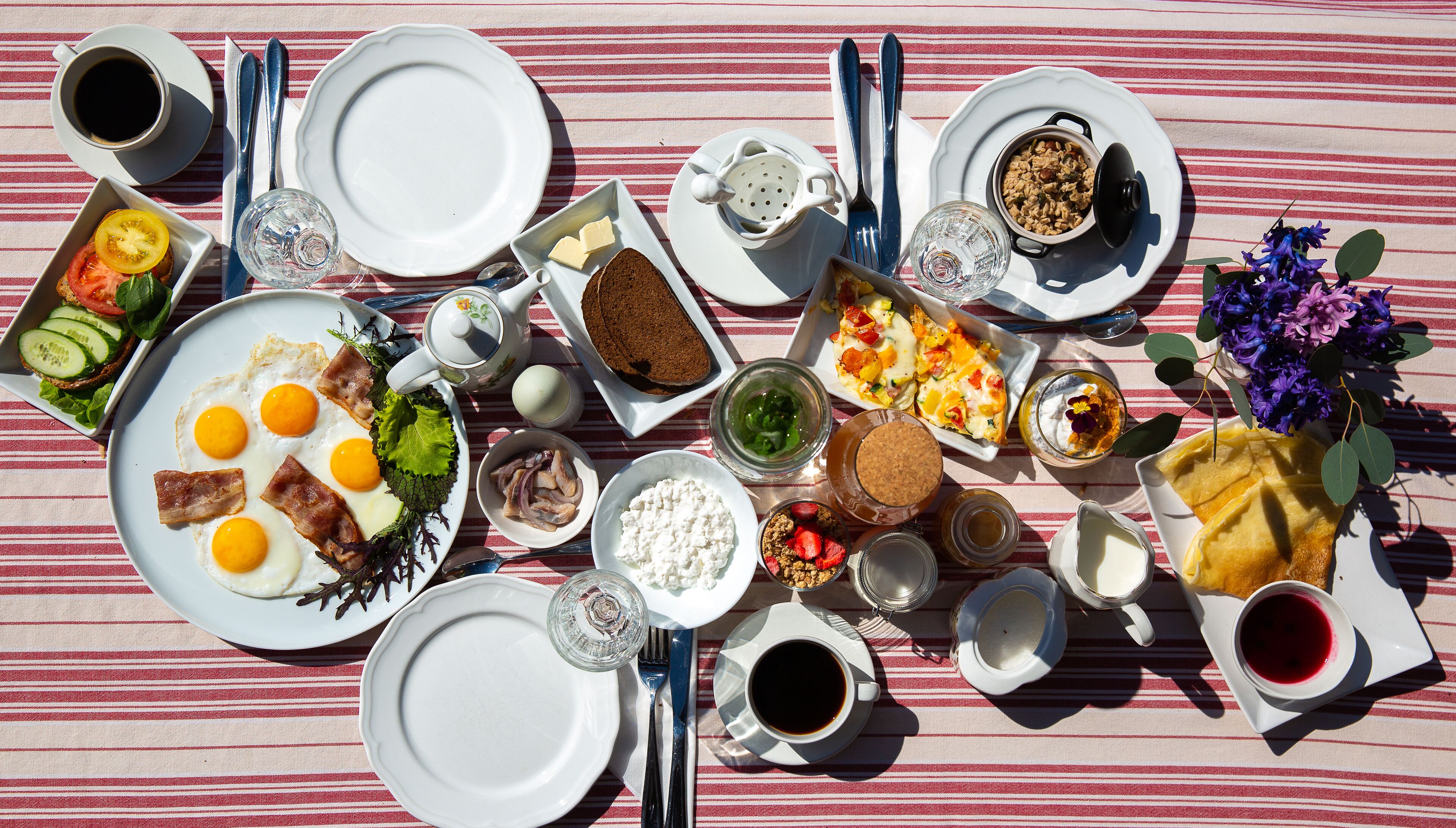 A table set with various breakfast items including eggs, bacon, toast, and fruit.