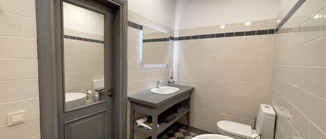 A modern bathroom with a large bathtub, a sink, and a toilet.