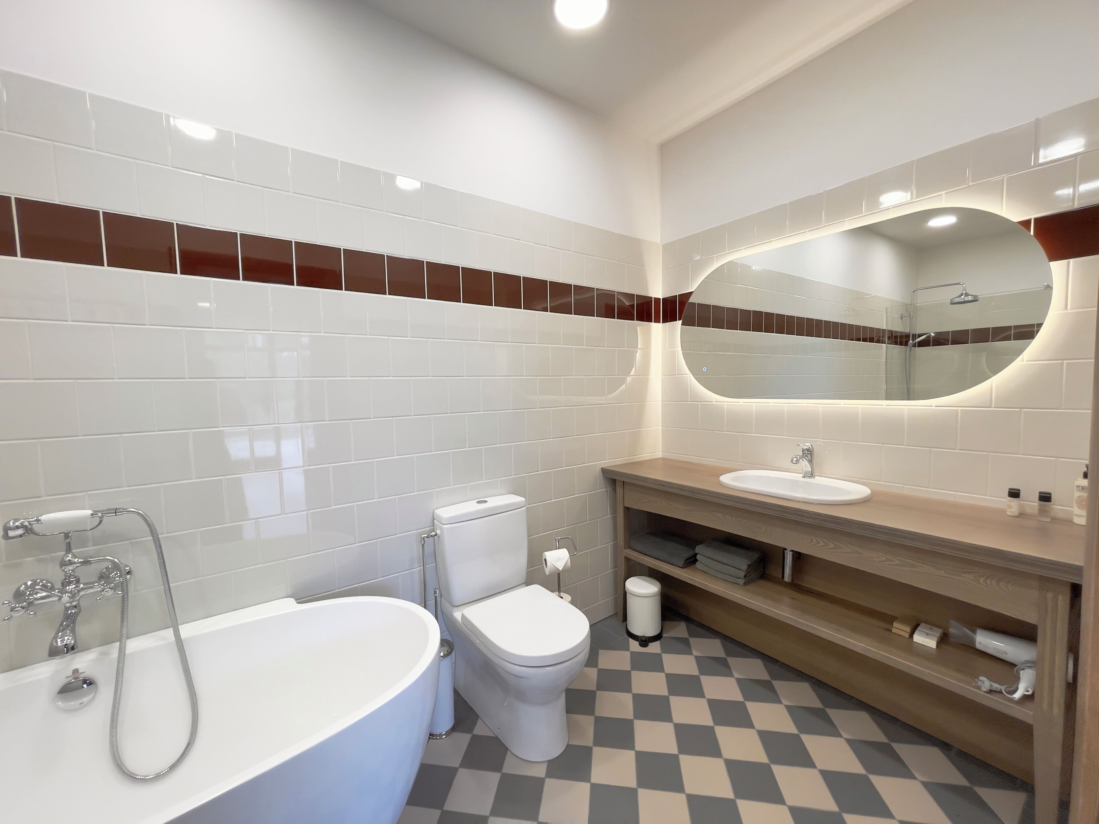 A modern bathroom with a white bathtub, a toilet, and a sink.