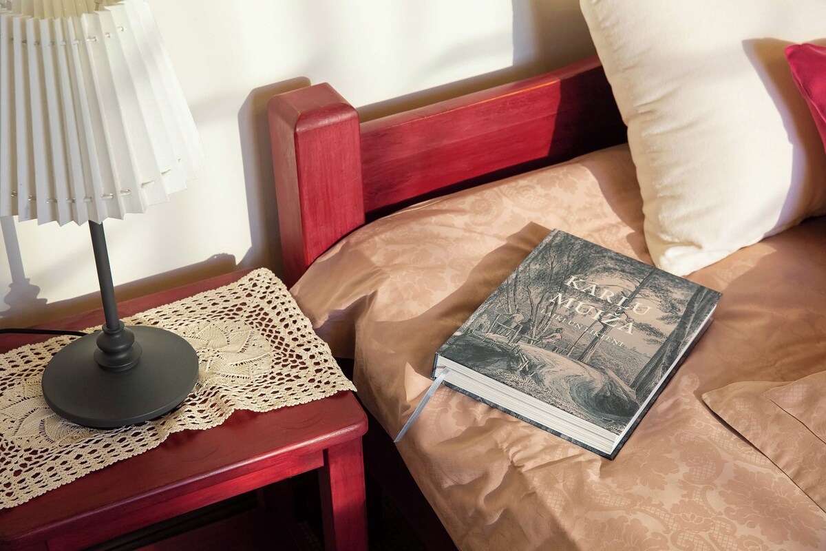 A bed with a book, a lamp, and a lace doily on a wooden nightstand.
