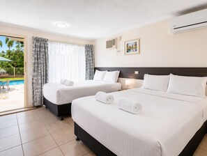 A hotel room with two beds, a pool view, and a ceiling fan. - Gallery Motel (South Murwillumbah)