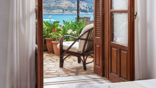 Una habitación con vista a un paisaje costero, una silla de mimbre y un cartel que indica un restaurante.
