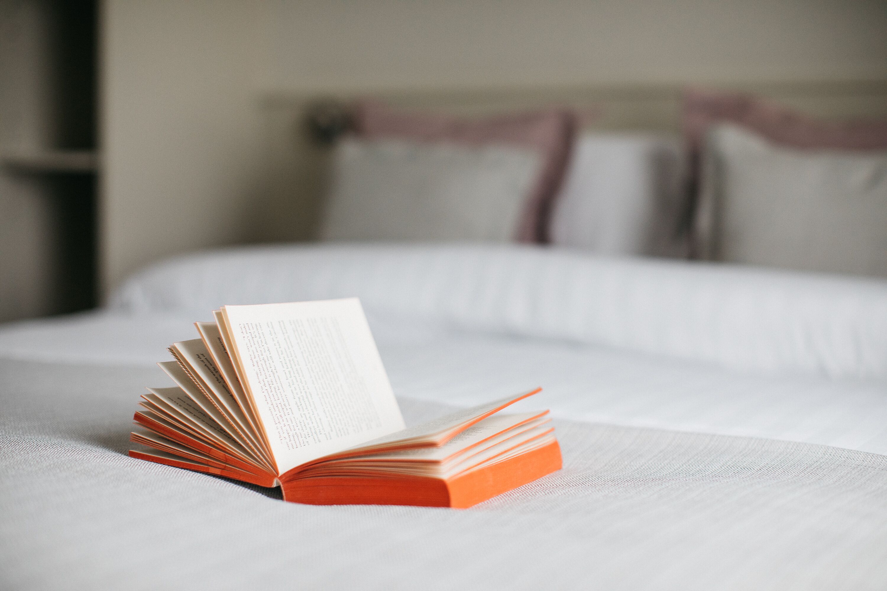 Een bed met een netjes opgevouwen boek erop.