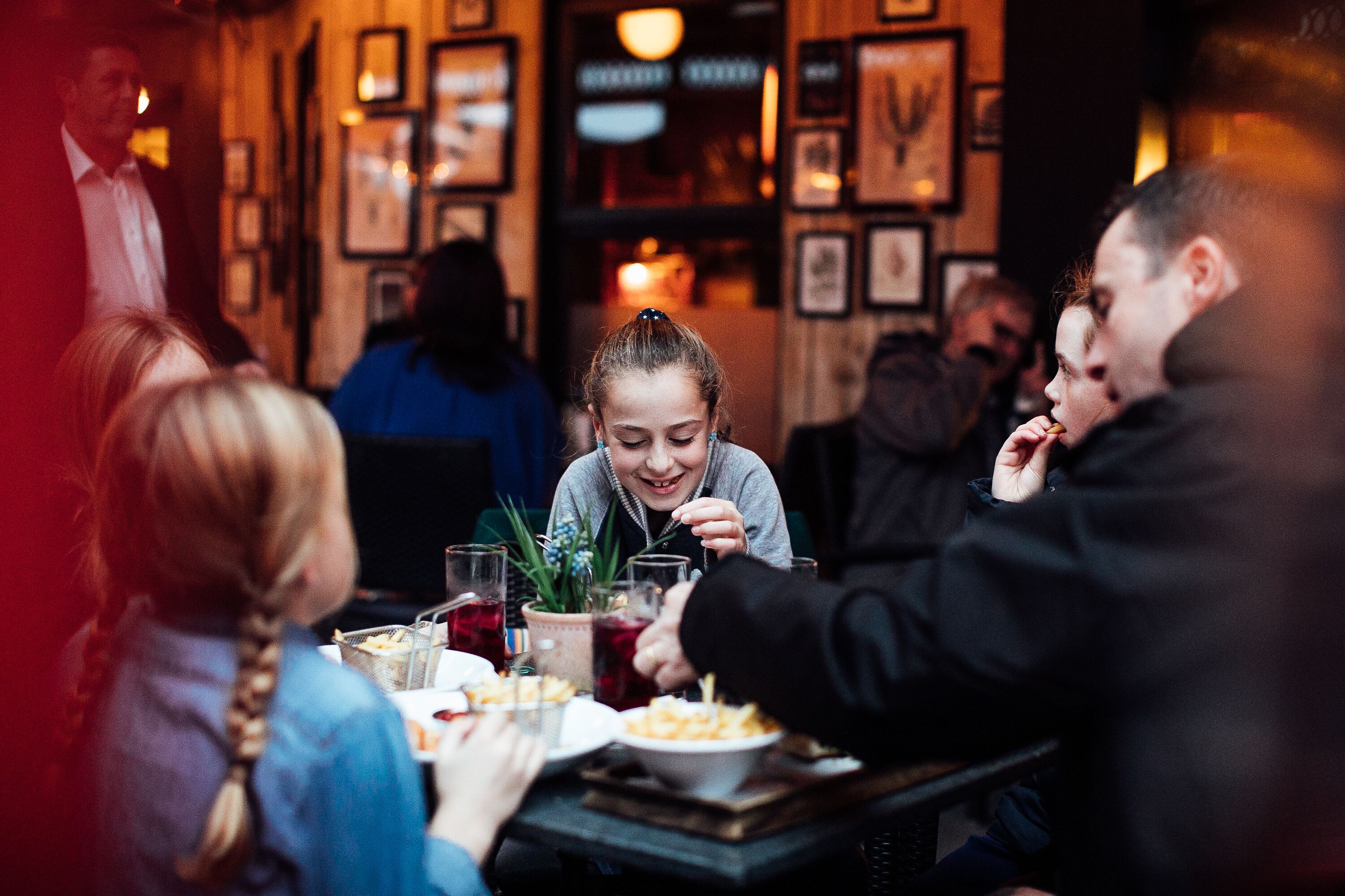 Un grup de persones dinuant en un restaurant amb interior acollidor i quadres als murs.