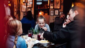 Un grup de persones dinuant en un restaurant amb interior acollidor i quadres als murs.