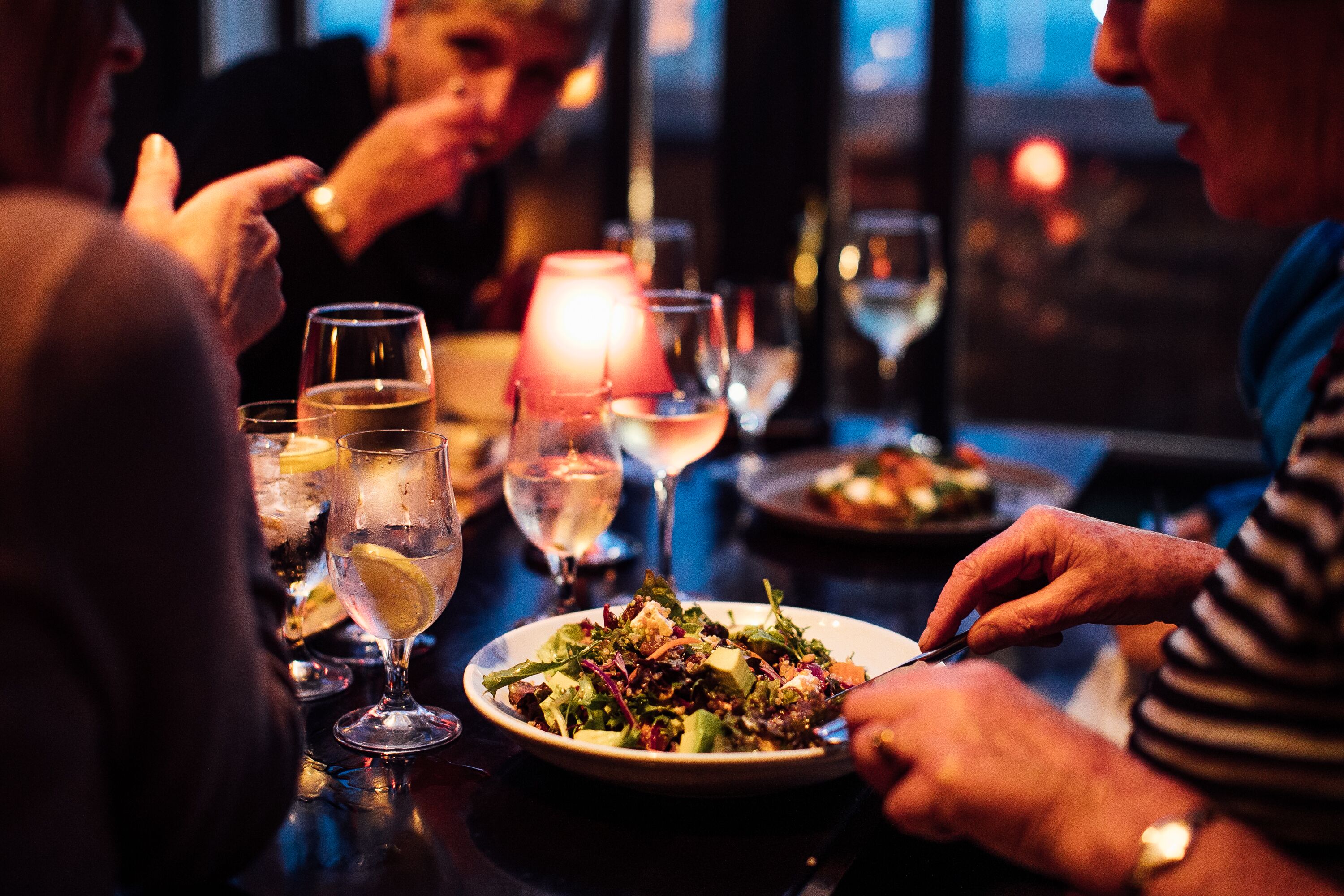 A dining table with a plate of food, glasses, and a candle.