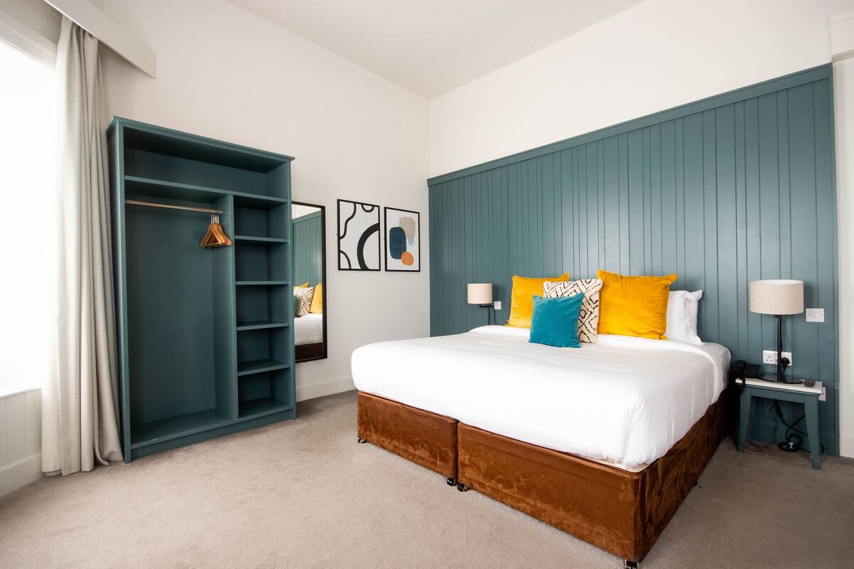 A bedroom with a large bed, a wardrobe, and a bedside table.