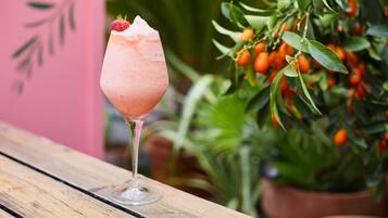 A cocktail glass with a strawberry garnish on a wooden table.