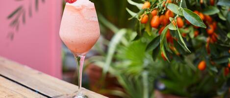 A cocktail glass with a strawberry garnish on a wooden table.