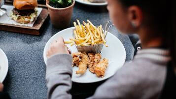 A dining table with a plate of fried chicken and French fries, a burger, and a small plant.