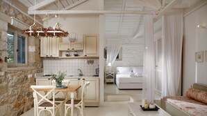 A cozy, well-lit room with a dining area, a bed, and a view of the outdoors. - Katikies Manis (West Mani)