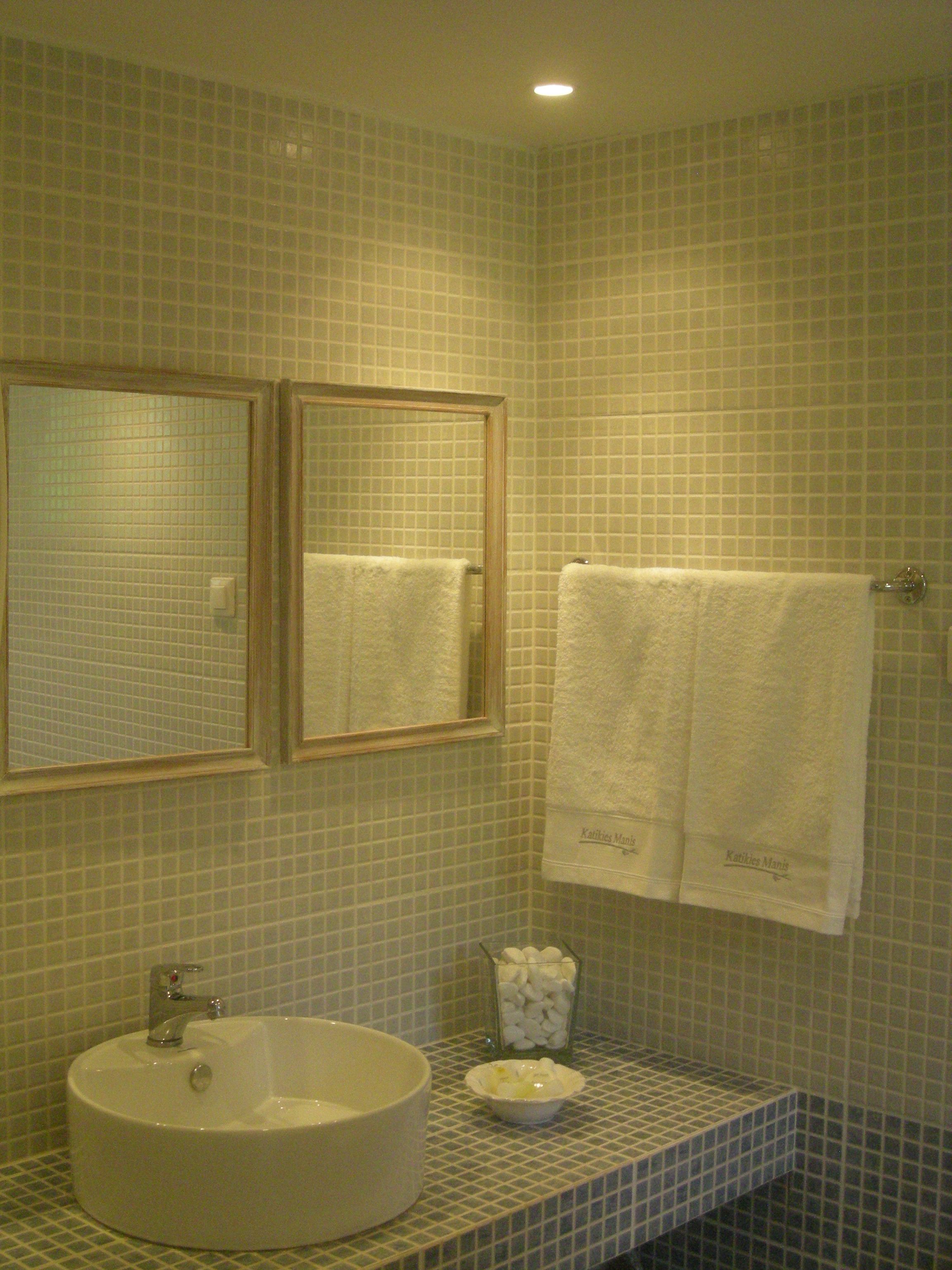 Un bagno con lavandino, specchio e due asciugamani appesi al muro.