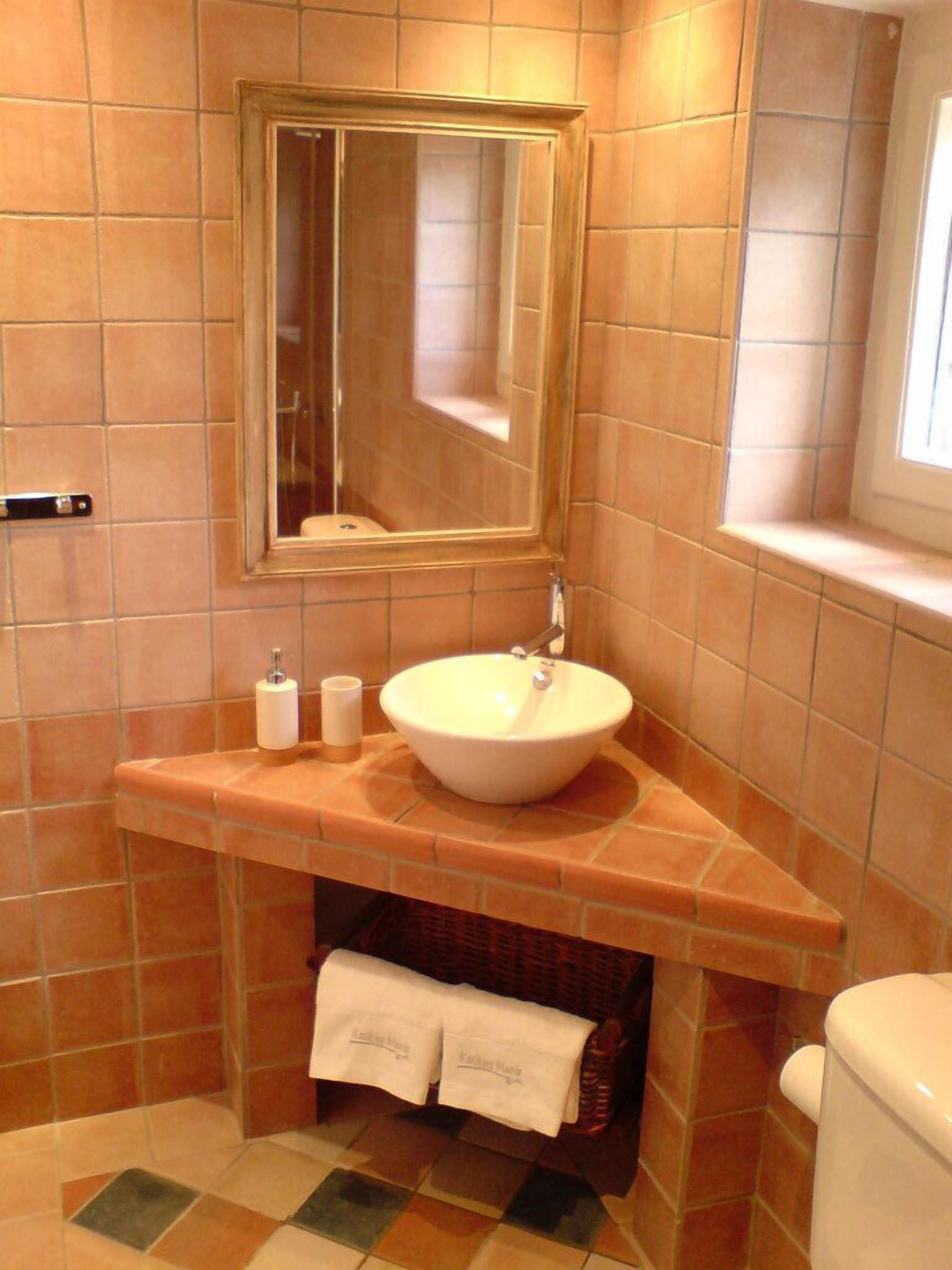 Une salle de bain avec un grand miroir, un lavabo blanc et des toilettes.