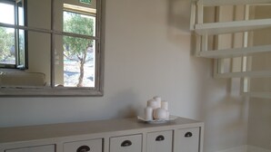 A bathroom with a white vanity, a mirror, and a window with a view of trees. - Katikies Manis (West Mani)