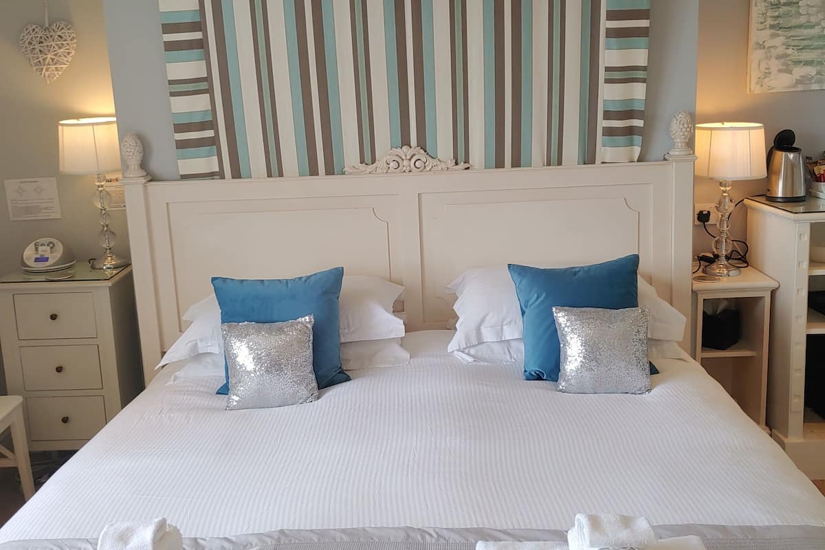 A hotel room with a large bed, two pillows, a nightstand, a lamp, and a decorative wall panel.