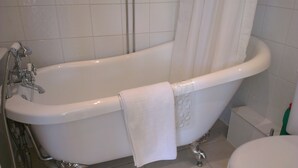 Una bañera blanca independiente con un cabezal de ducha y una toalla colgada.