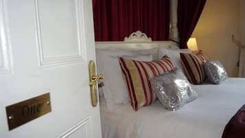 Habitación de hotel con una cama, una puerta con el rótulo 'One' y una cortina roja.