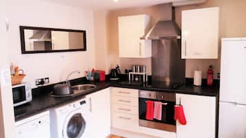 A compact kitchen with a washing machine, a microwave, a sink, and a stove.