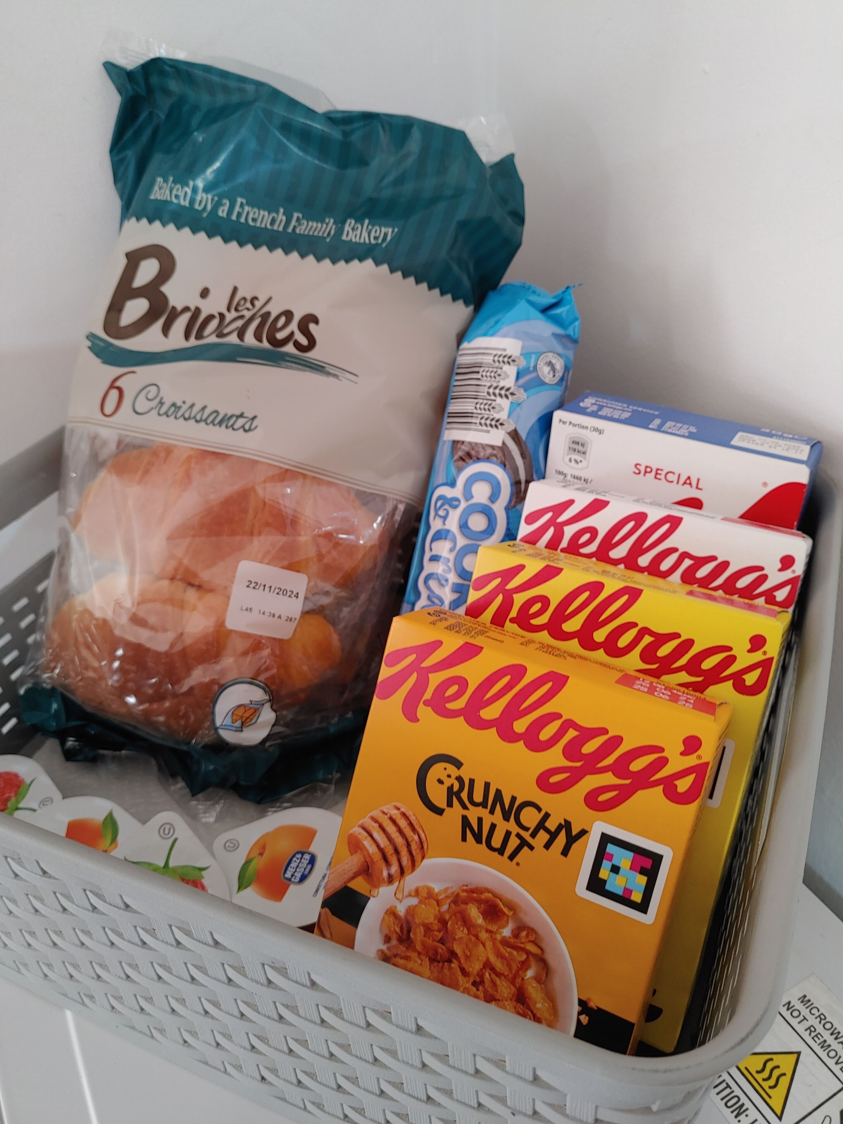 Un panier contenant un paquet de croissants à la brioche, un sachet de céréales Kellogg’s Crunchy Nut et une boîte de céréales Kellogg’s Special K.