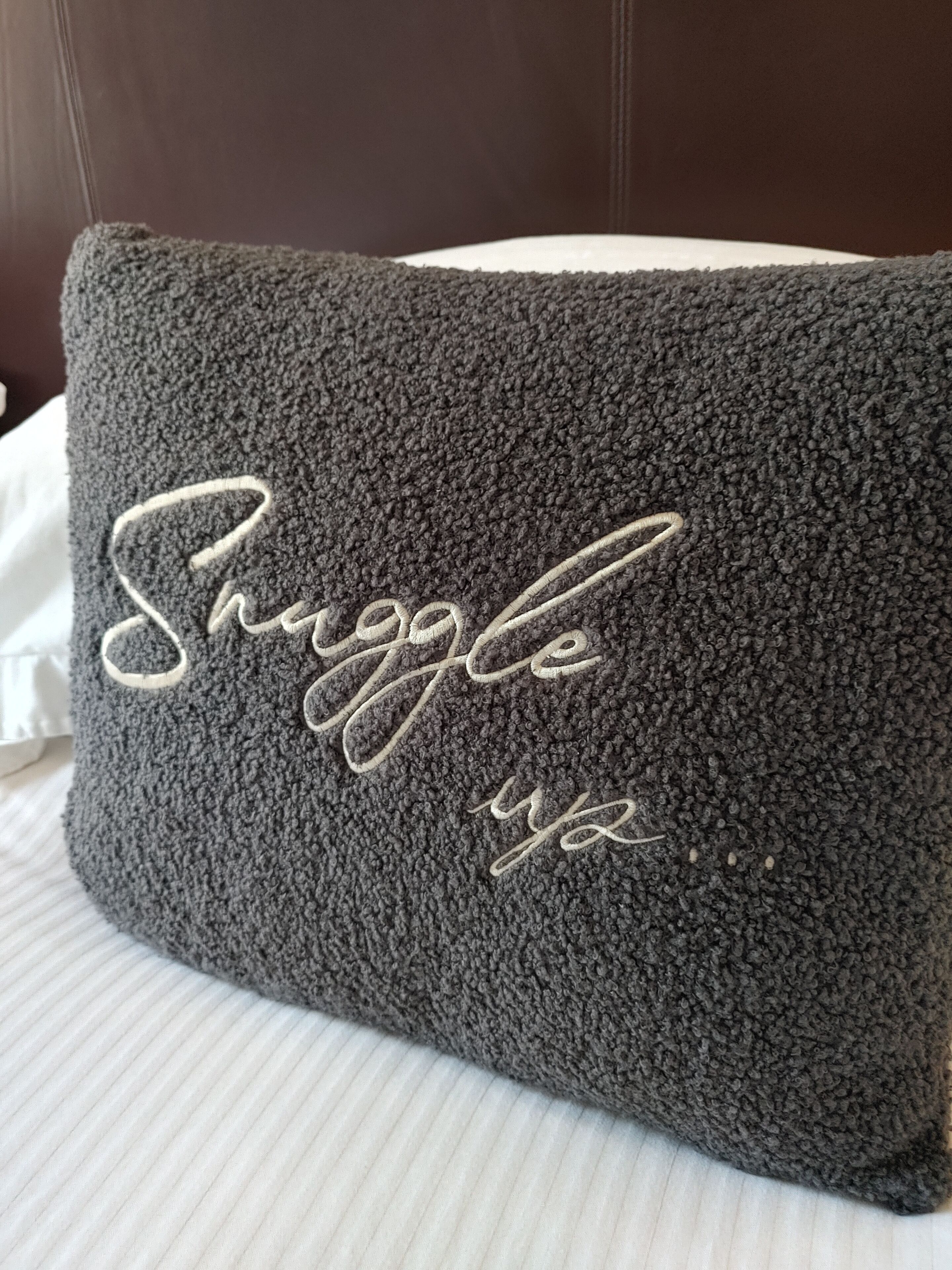 A dark gray textured pillow with the word "Struggle" embroidered in white.