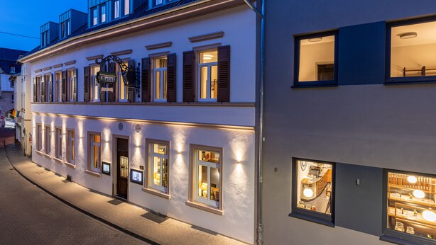 Un bâtiment à deux étages, doté de fenêtres illuminées et d’un restaurant visible au rez-de-chaussée.