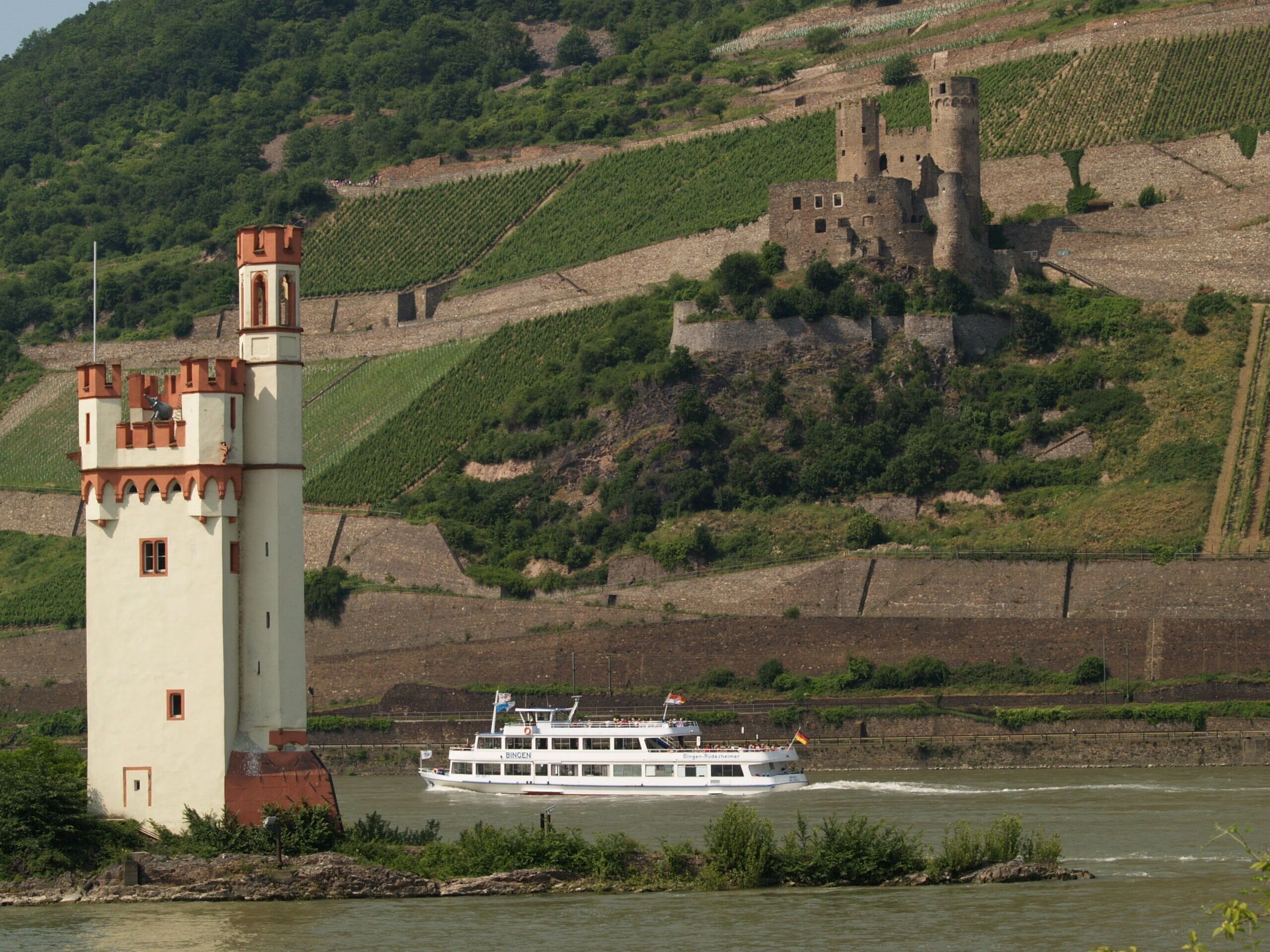 Eine Burg auf einem Hügel mit einem Turm und einem Boot auf dem Fluss.