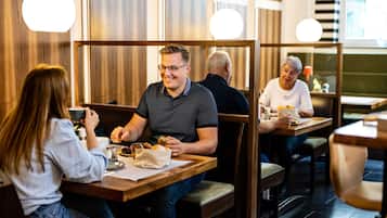 Restaurante com paredes de painel de madeira, cabines individuais e iluminação pendente.