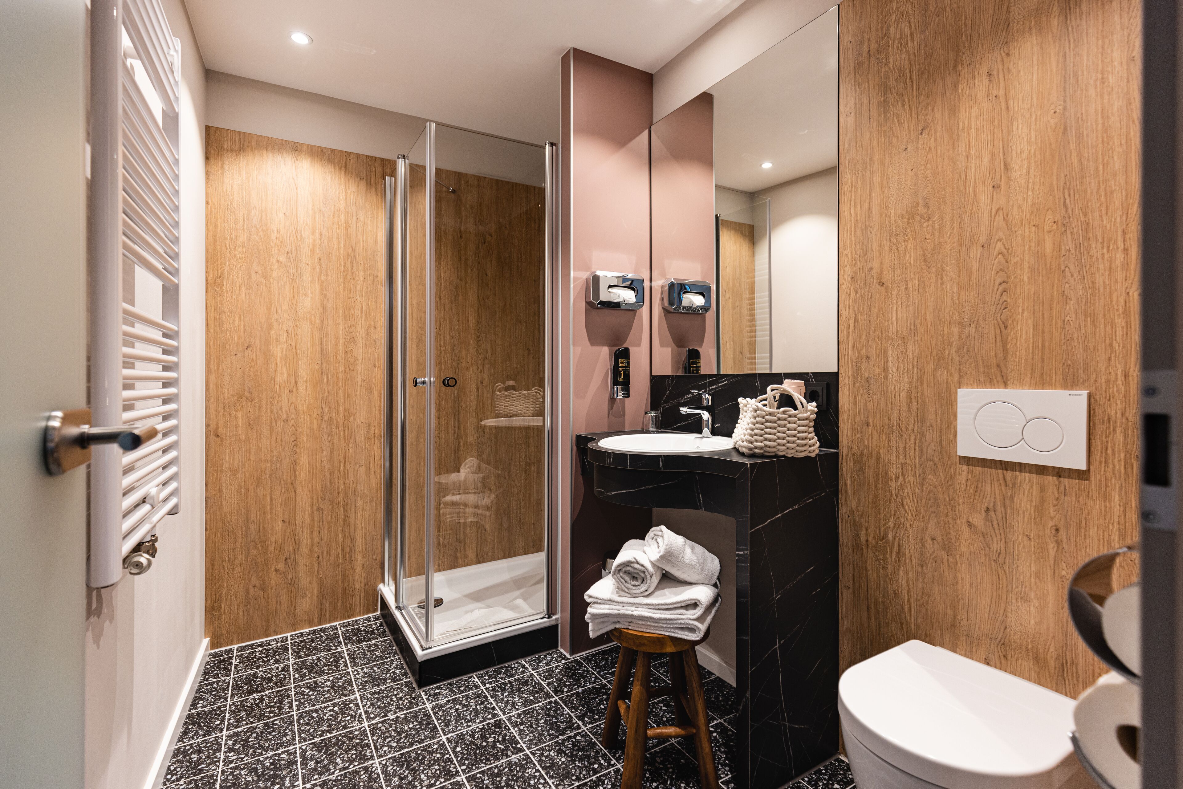Un baño moderno con cabina de ducha de vidrio, tocador de madera y inodoro blanco.