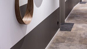 Un couloir avec trois miroirs fixés au mur et un sol recouvert de moquette.