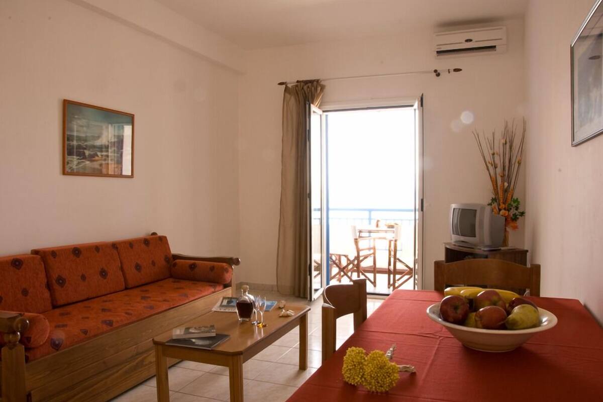 A living room with a sofa, a table with a bowl of fruit, a television, and a painting on the wall.