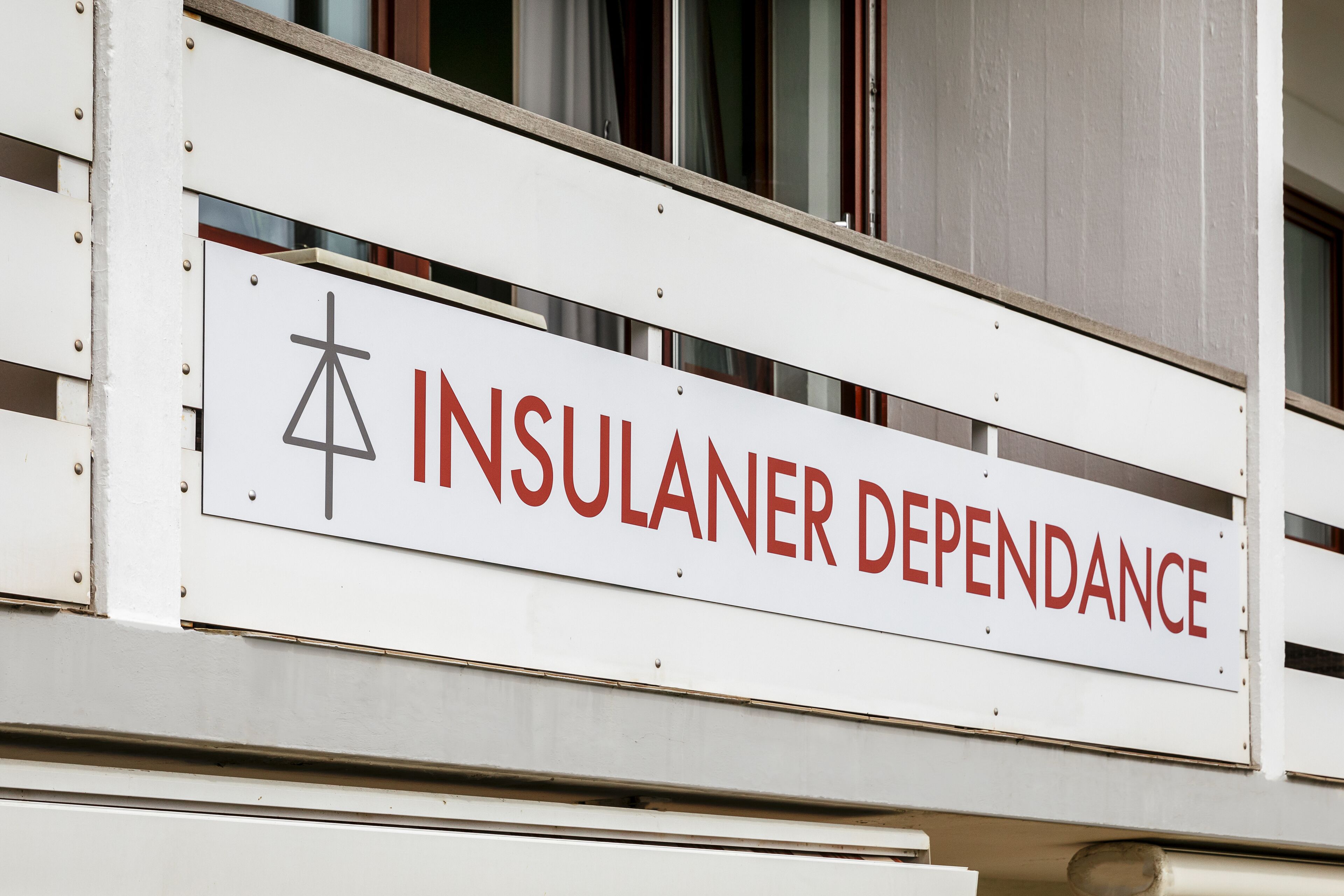 Un letrero con el texto "INSULANER DEPENDANCE" y un símbolo.