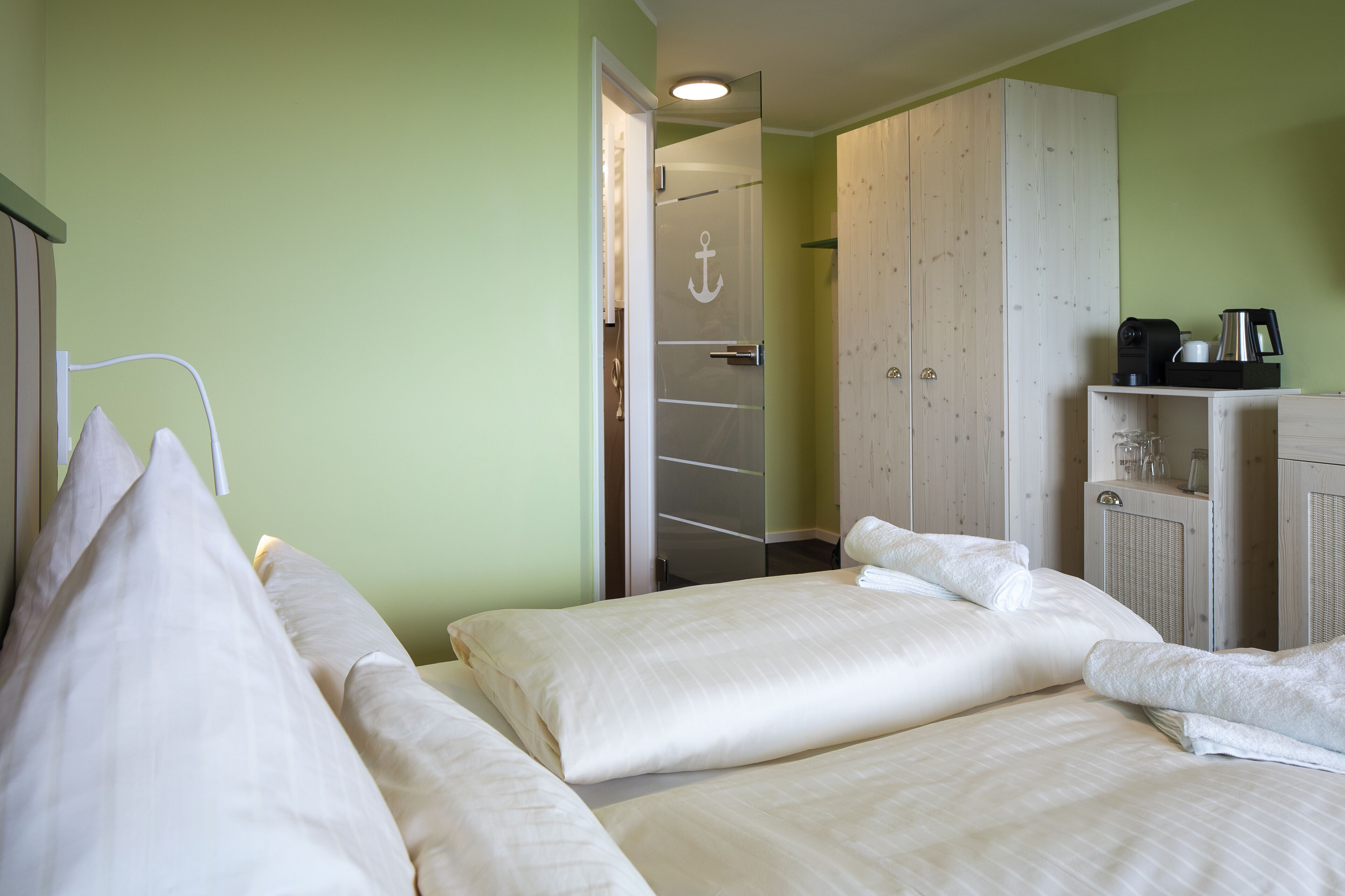 Ett hotellrum med två sängar, en garderob och ett litet köksutrymme.