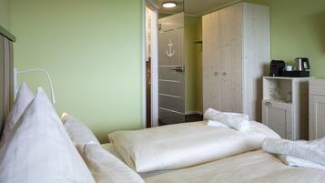 Ett hotellrum med två sängar, en garderob och ett litet köksutrymme.