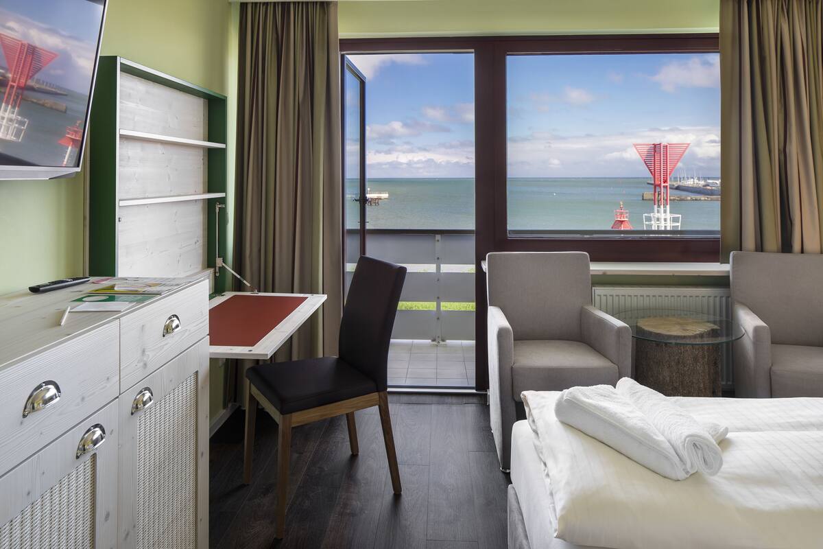 A hotel room with a bed, a desk, a chair, and a TV.