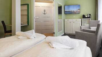 Een hotelkamer met twee bedden, een stoel, een bureau, een televisie en een schilderij aan de muur.