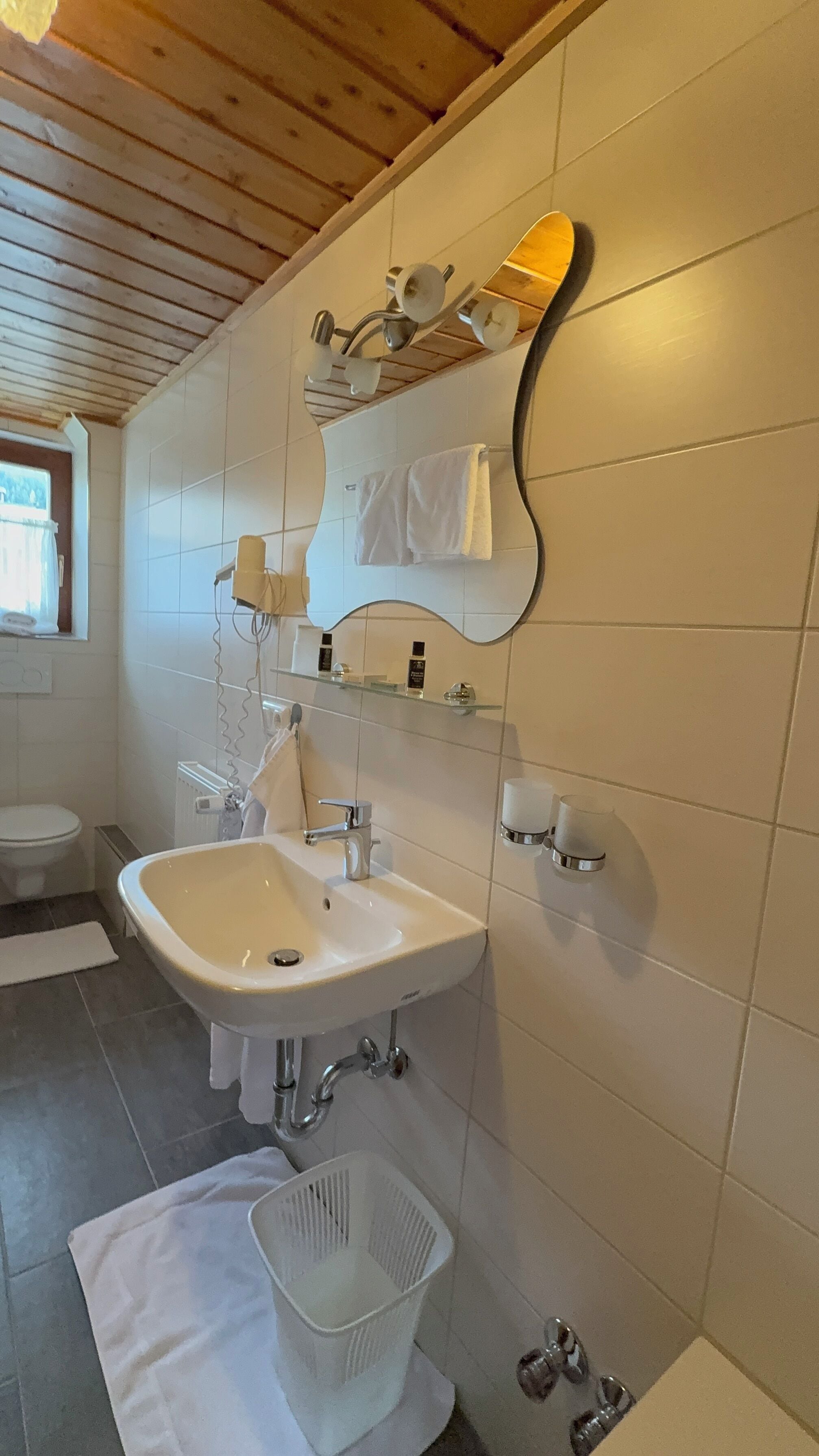 A bathroom with a white sink, a mirror, a towel rack, and a shower area.
