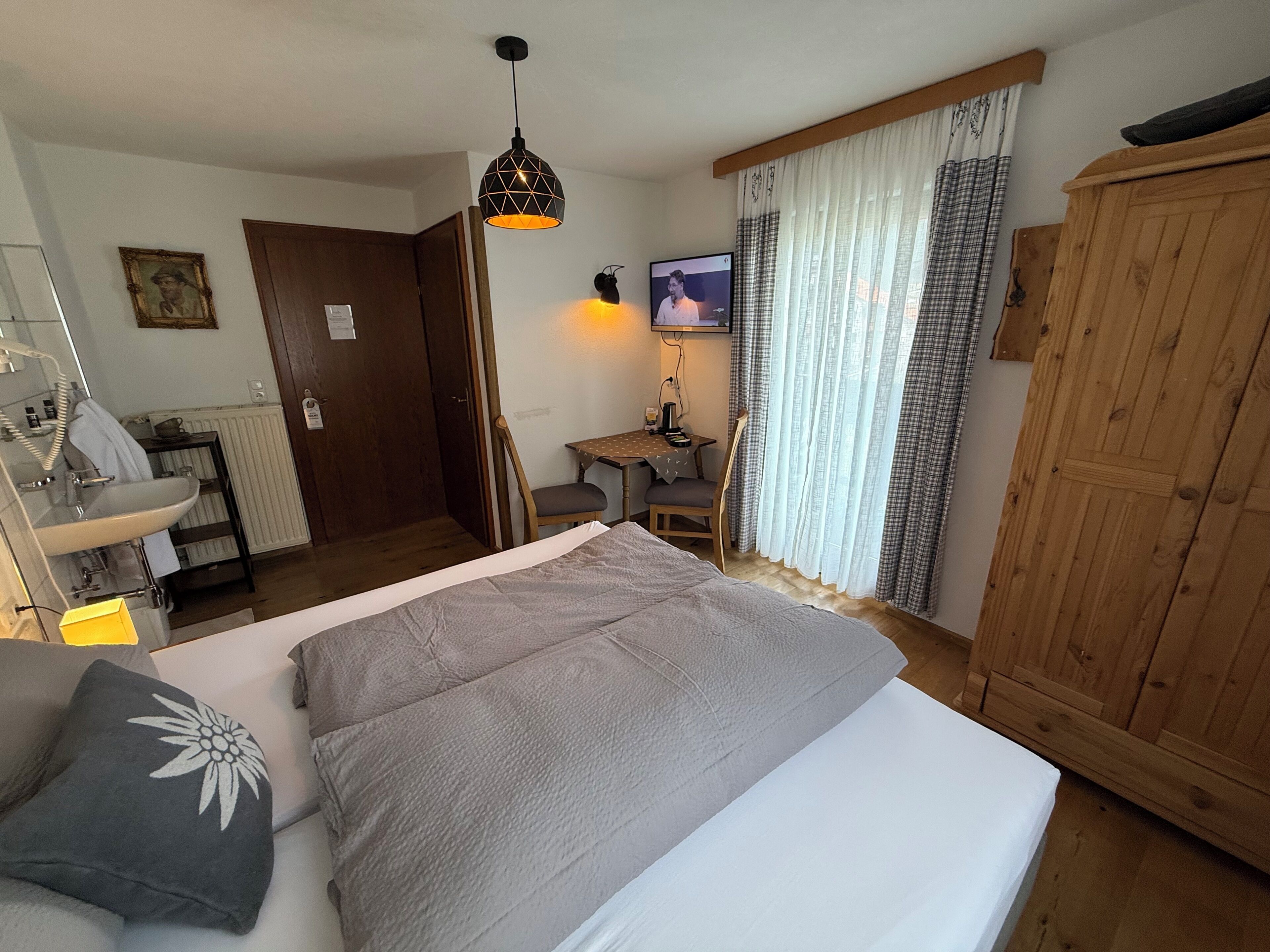 Een slaapkamer met een bed, een bureau, een stoel, een televisie en een kledingkast.